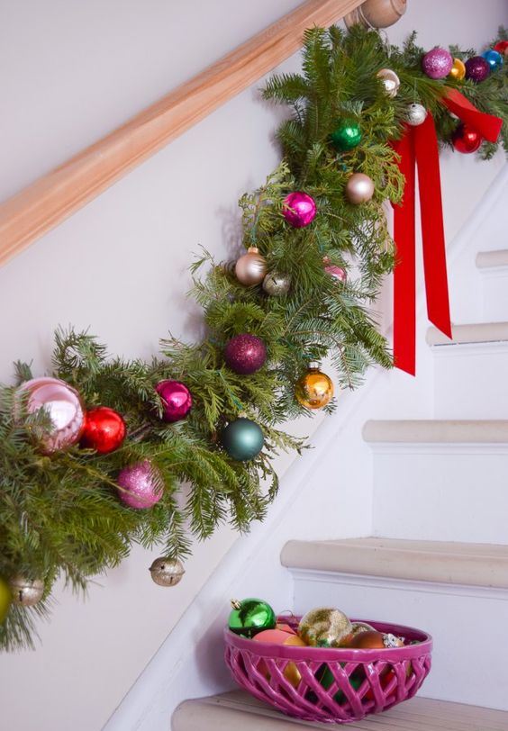 Girlanda ukrašena božićnim kuglicama i mašnama, obješena na stepenicama
